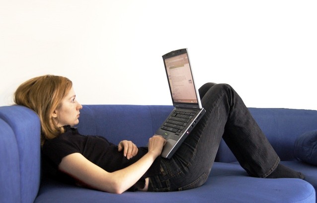 žena sedící na pohovce a pracující na notebooku